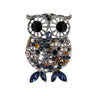 Owl brooch with silver-tone detailing, large black eyes, and blue, orange, pink, and iridescent faceted stones. Blue marquise-cut stones for feet. Cutout on white.