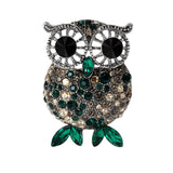 Owl brooch with silver-tone frame, black eyes, and faceted stones in shades of green and beige, finished with green navette-shaped stones for feet. Cutout on white.
