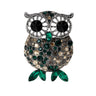 Owl brooch with silver-tone frame, black eyes, and faceted stones in shades of green and beige, finished with green navette-shaped stones for feet. Cutout on white.