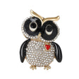 Owl brooch with black round faceted rhinestone eyes and black enamel wings, clear pave stones on the body, red heart detail, and gold-tone accents, cutout on white.