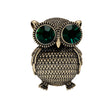 Owl brooch with textured gold-tone metal finish and large green faceted stone eyes, cutout on white background.