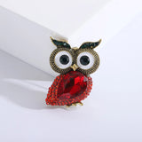 Owl brooch with bright red faceted stone body, small red decorative stones, and green eyes, upright pose on white background.