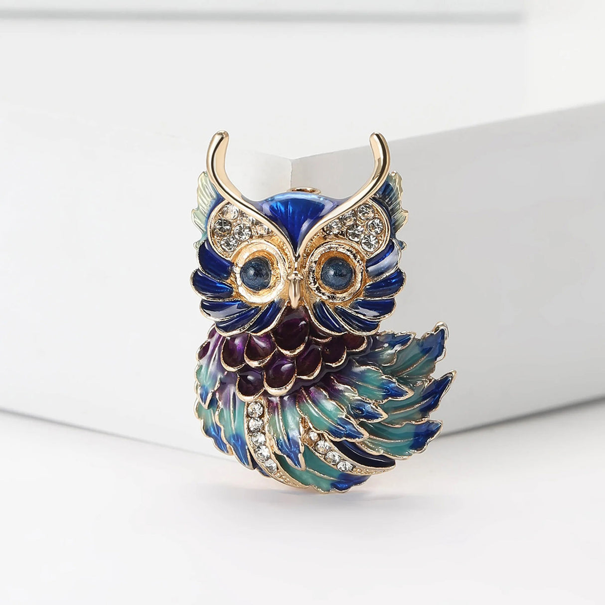 Owl brooch featuring blue, green, and purple enamel feathers with gold-tone detailing and clear stones, upright pose.