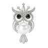 Owl brooch with silver-tone metal finish, eyes from black faceted stones, small clear crystal accents, and large white round imitation pearl body, cutout on white.