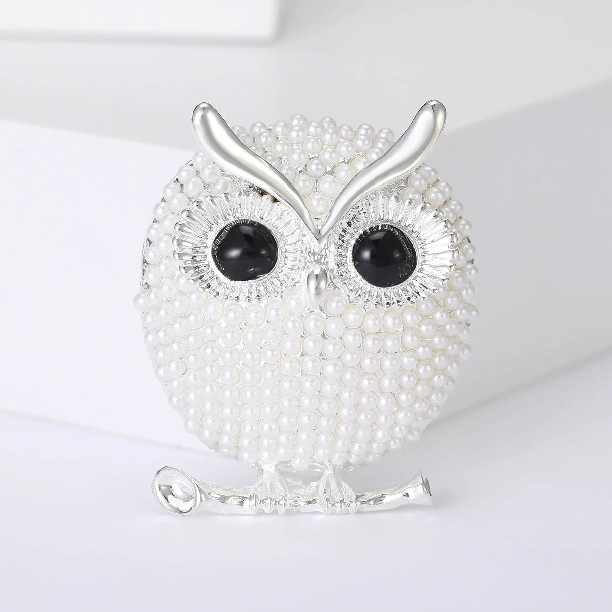 Owl brooch with white round beads, black eyes, and silver-tone metal finish, upright studio pose on white background.