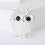 Owl brooch with white round beads, black eyes, and silver-tone metal finish, upright studio pose on white background.