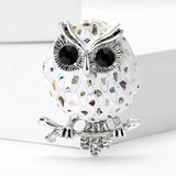 Owl brooch with white-tone mosaic body resembling abalone shell, multicolor reflective accents, and silver-tone branch perch, cutout on white.