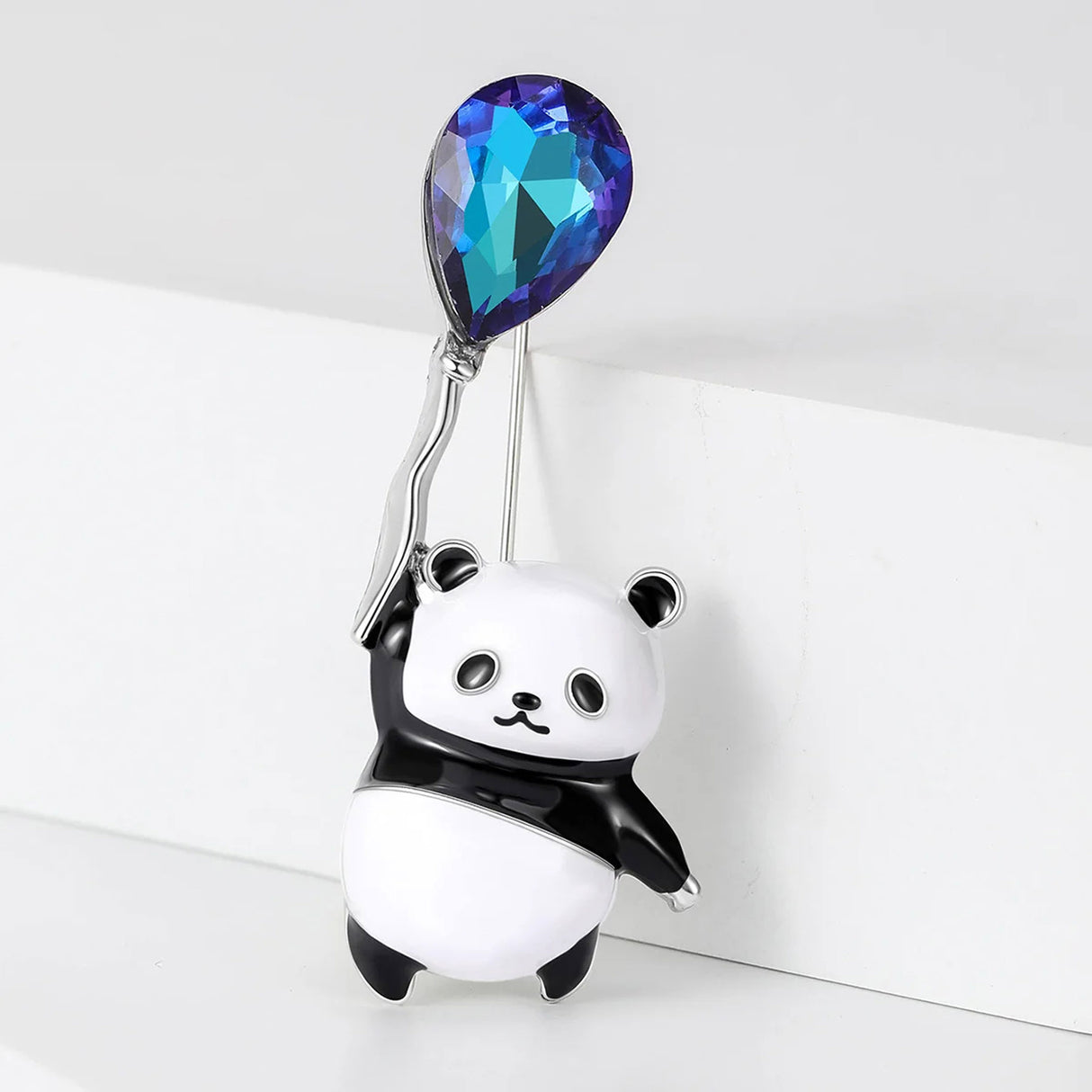 Panda brooch with glossy black and white enamel and blue-toned faceted balloon stone, upright pose against white backdrop.