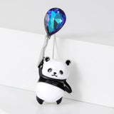 Panda brooch with glossy black and white enamel and blue-toned faceted balloon stone, upright pose against white backdrop.