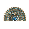 Peacock brooch with teal faceted stones, gold-tone metal, and dark blue teardrop center stone, cutout on white.