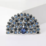 Peacock brooch in silver-tone with alternating light and dark blue stones and faceted teardrop centerpiece, cutout view.