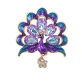 Peacock brooch with purple and blue enamel feathers, accented by large faceted stones, and flower drop with small clear stones. Cutout on white.