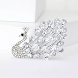 Peacock brooch with clear teardrop faceted stones and silver-tone base, upright pose on white background.