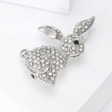 Bunny brooch in silver-tone finish with clear faceted stones and black eye, angled view on white surface.