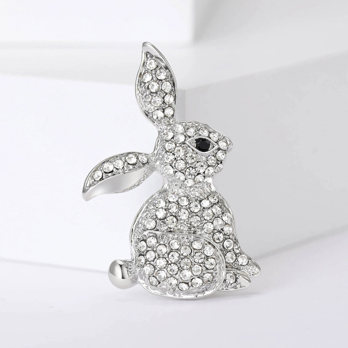 Bunny brooch with silver-tone metal, clear faceted stones, and black eye detail, upright pose on white background.