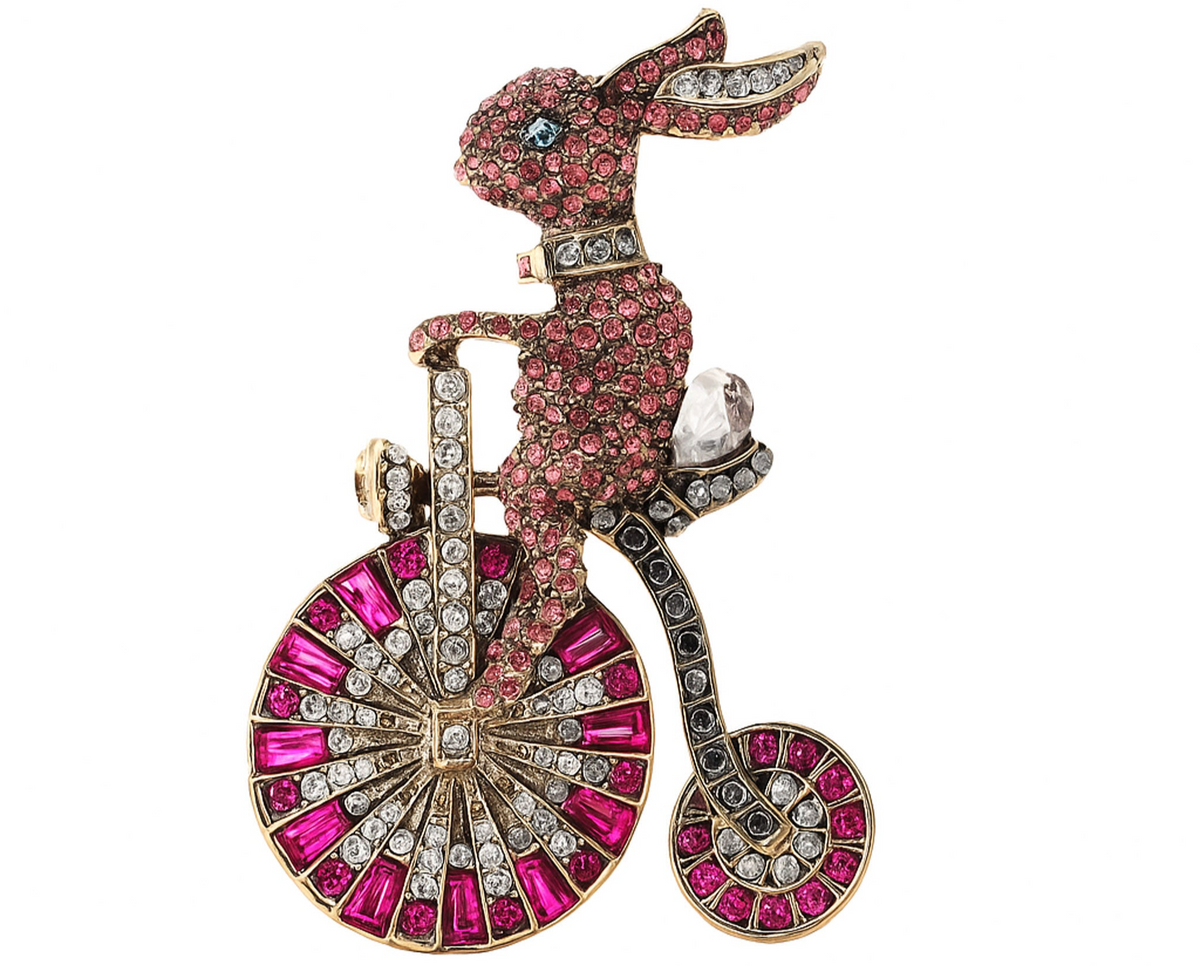 Bunny brooch with pink rhinestone pave, riding a bicycle with clear and magenta stone wheels. Cutout on white background. Landscape crop for secondary use.