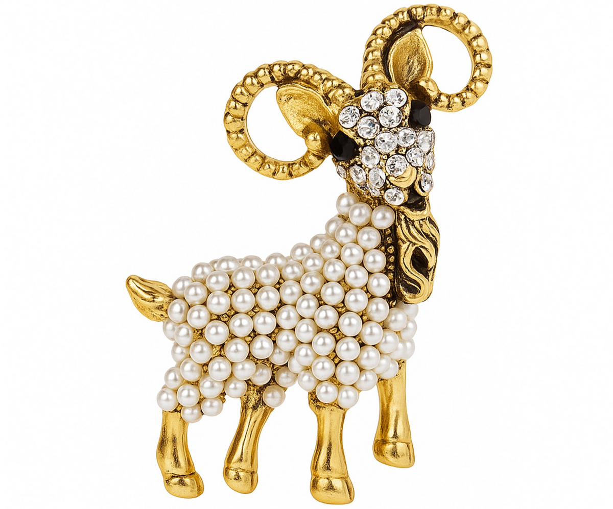 Ram brooch with gold-tone metal finish, clear faceted stones on face, and white round beads on body. Cutout on white background. Landscape crop for secondary use.