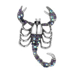 Scorpion brooch with silver-tone body, purple-blue iridescent stones, and raised claws, isolated on white background.