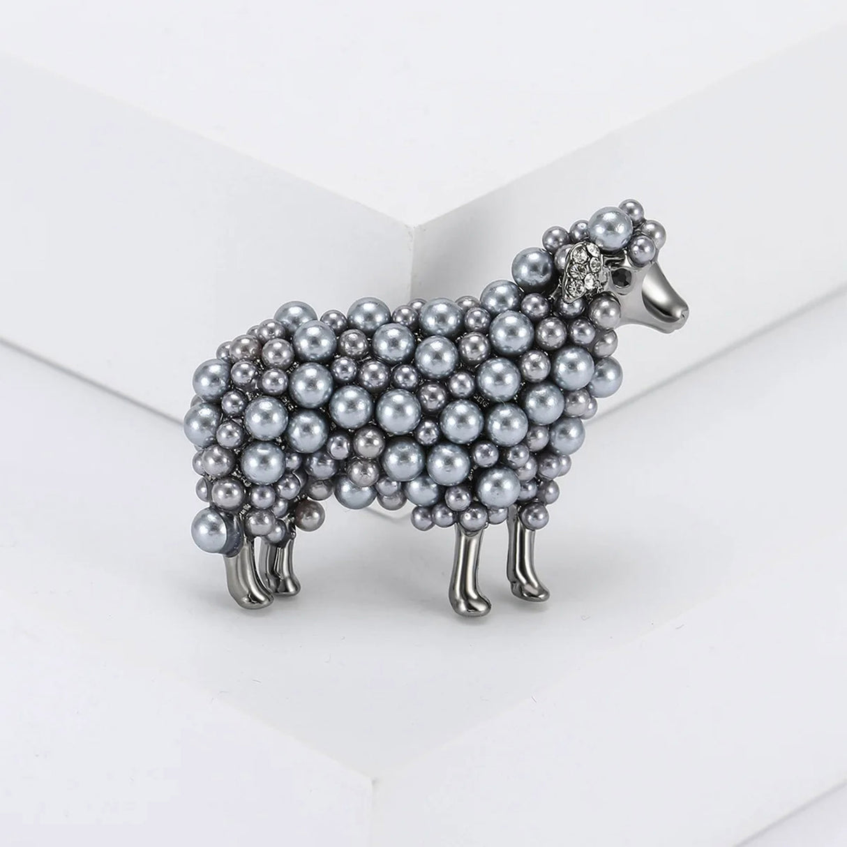 Sheep brooch in grey-tone metal with mixed-size faux pearls, upright view on white background.