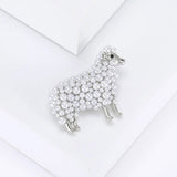 Sheep brooch with silver-tone metal, clustered white round beads, and small clear crystal ear accents, angled top view on white surface in studio.