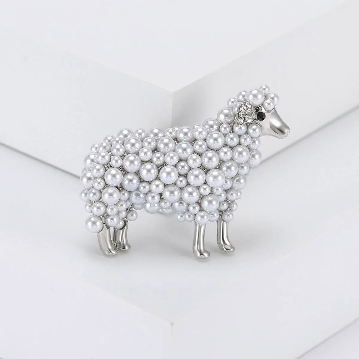 Sheep brooch in silver-tone metal with layered white round beads and crystal ear detailing, upright view on white studio background.
