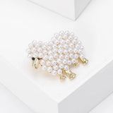 Sheep brooch with gold-tone metal finish and clustered white faux pearls forming the body, angled top view on white block.