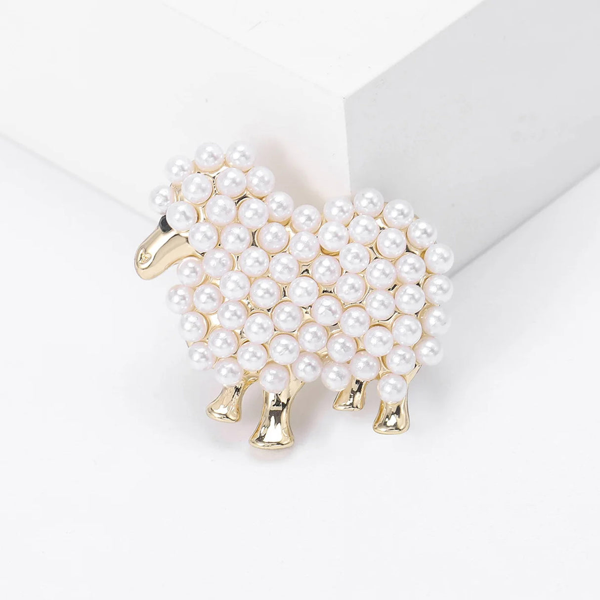 Sheep brooch in gold-tone metal with dense white round beads, standing upright against white studio background.