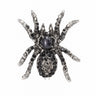 Tarantula brooch with silver-tone base, black and clear faceted stones, and a dark oval cabochon center, cutout on white.
