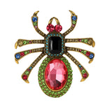 Spider brooch with bright pink and black faceted center stones forming the body, and multicolor stones on gold-tone legs. Cutout on white background.