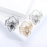 Set of three spider brooches in gunmetal, gold-tone, and silver-tone finishes with black and clear faceted stones, flat lay on white.