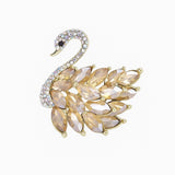 Swan brooch with gold-tone metal base, light amber-colored marquise-cut faceted stones, and crystal-paved neck, cutout on white.