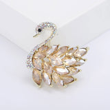 Swan brooch with gold-tone metal base, amber-colored marquise-cut faceted stones, and multicolor pavé head, front view in white studio setting.