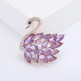 Swan brooch with rose gold-tone base, purple faceted marquise stones, and pavé crystal head, front view in studio.
