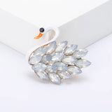 Swan brooch featuring smooth white body, faceted translucent stones, and orange beak, front view on white surface.