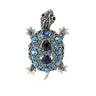 Tortoise brooch with silver-tone metal finish, dark blue center stones, and light blue faceted accents, cutout on white.