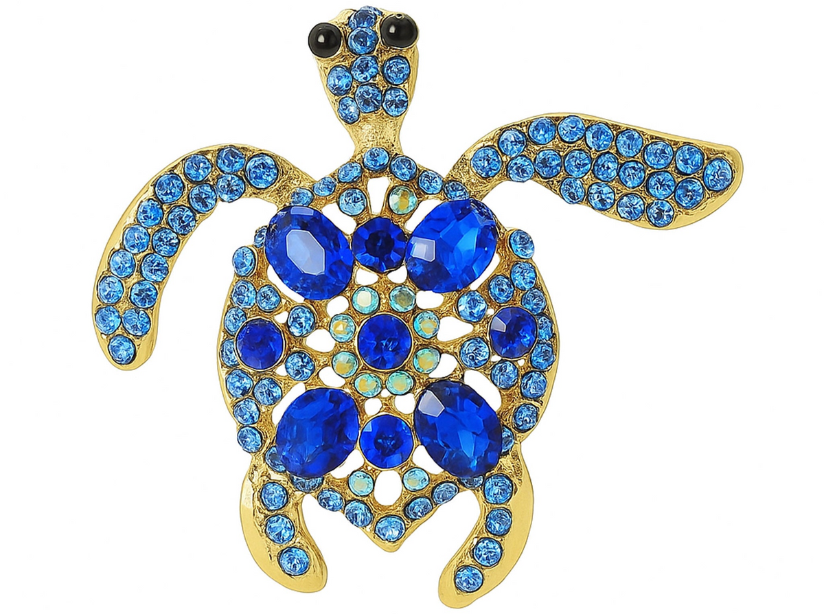 Sea turtle brooch in gold-tone metal base, with blue faceted center stones surrounded by small round accent crystals. Cutout on white background. Landscape crop for secondary use.
