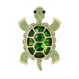 Tortoise brooch with large green faceted center stone and small round accents, set in gold-tone frame. Cutout on white background.