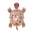 Tortoise brooch with large pink faceted center stone, small round accents, and gold-tone edging. Cutout on white background.