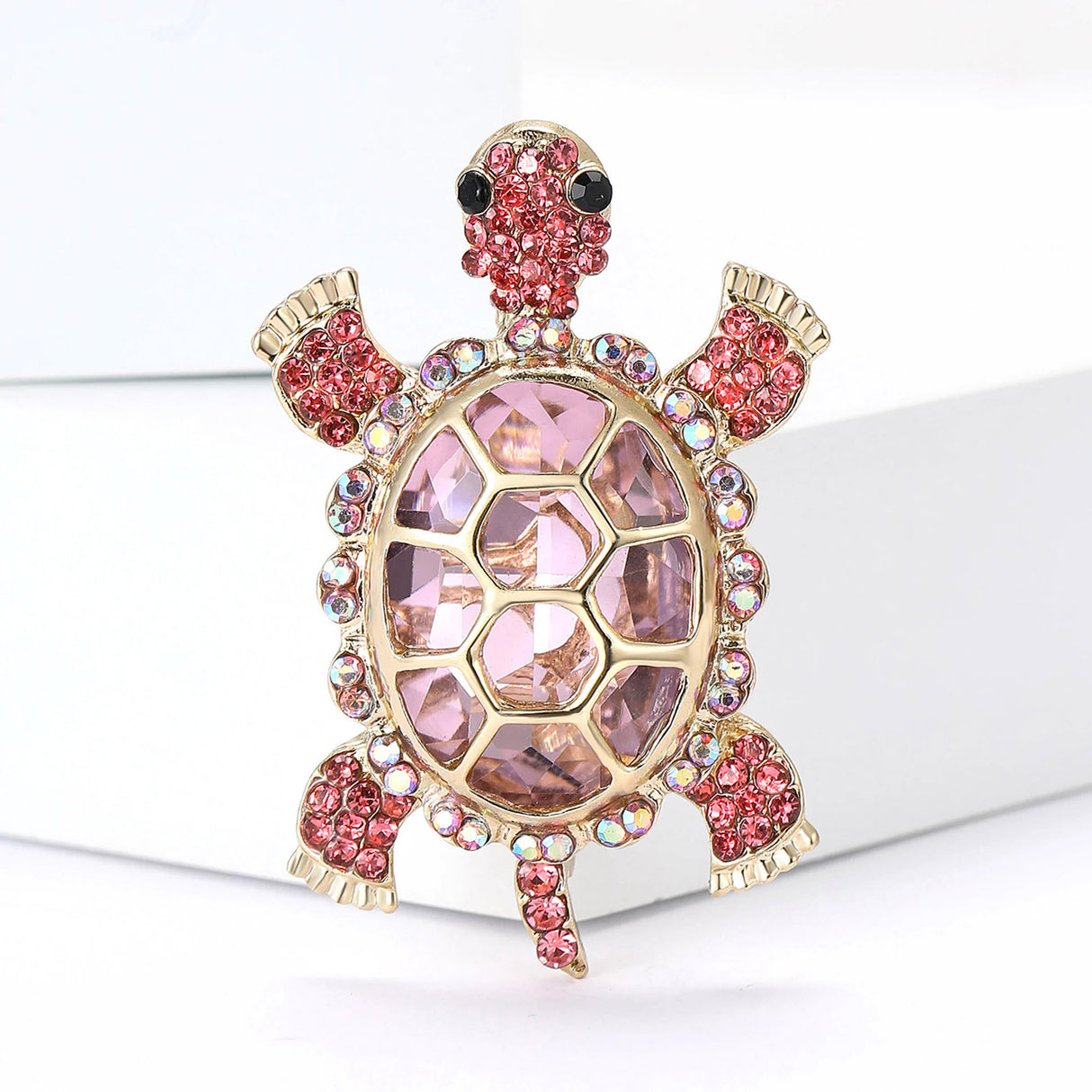 Turtle brooch with large pink faceted shell stone, bright pink round details, and gold-tone outline, upright pose on white background.